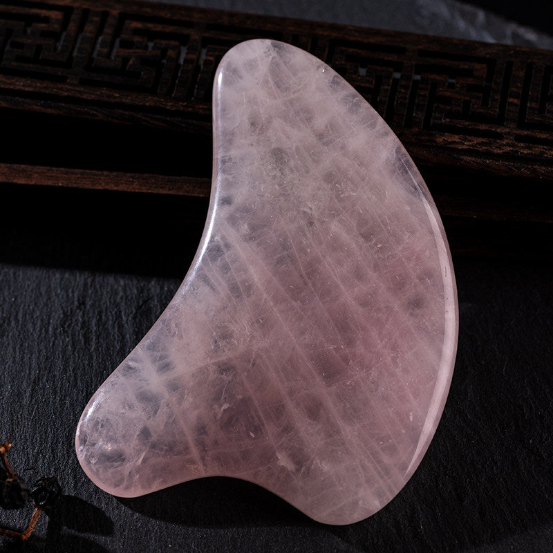 Rose quartz gua sha tools arranged on a vanity